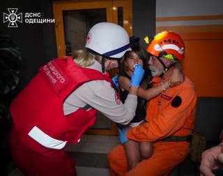 Paramedics assist a girl at the site of an apartment building hit by a Russian drone strike in Odesa, Ukraine